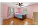 Pink bedroom features wood floors, ceiling fan, window with curtains, and queen bed at 237 Palaside Ne Dr, Concord, NC 28025