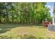 A lush backyard features a border of tall trees, a grass lawn, and a wood deck at 2512 Pimpernel Rd, Charlotte, NC 28213