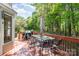 View of a wood deck with a glass table, grill, and outdoor seating surrounded by lush greenery at 2512 Pimpernel Rd, Charlotte, NC 28213