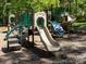 A playground with tan slides, green railings, and a textured blue climbing wall on a wood chip surface at 2906 Crescent Knoll Dr, Matthews, NC 28105