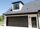 A detached, brick two-car garage featuring a black door, adjacent to an entrance door, and dormer at 3500 Manna Ln, Mount Holly, NC 28120