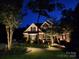 Home at night with illuminated landscaping, lush garden beds, and a cozy front porch at 4715 Amberside Dr, Rock Hill, SC 29732