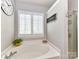 Bright bathroom showcasing a bathtub, custom shower and a shuttered window for natural lighting at 5301 Greyfriar Ct, Waxhaw, NC 28173