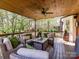 Covered deck with ceiling fan and patio seating with view of wooded backyard at 5301 Greyfriar Ct, Waxhaw, NC 28173