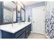Bathroom boasting light blue walls, a vanity with double sinks, framed mirrors, and a shower with curtain at 7034 Leaves Ln, Charlotte, NC 28213