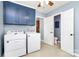 Laundry room with blue cabinets, a Whirlpool washer and dryer, and a door leading to a bathroom at 7034 Leaves Ln, Charlotte, NC 28213