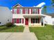 Inviting two-story home featuring a well-manicured lawn, red shutters, and a charming front porch at 7147 Henderson Valley Ln, Charlotte, NC 28269