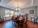 Formal dining room featuring hardwood floors, a tray ceiling, and a classic chandelier at 9622 Harvest Pond Nw Dr, Concord, NC 28027