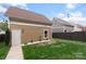 Backyard featuring a well-maintained lawn, privacy fence, detached garage, and ambient string lighting at 1117 Cedar Park Dr, Pineville, NC 28134