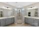 Bathroom showcasing a glass shower enclosure, neutral tile, double sink vanity, and walk-in closet at 1117 Cedar Park Dr, Pineville, NC 28134