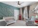 Charming Bedroom with a custom accent wall, white crib, ceiling fan and a cozy chair with accent lighting at 1117 Cedar Park Dr, Pineville, NC 28134