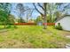 Large, grassy backyard with mature trees, a storage shed, and a wooden fence at 1212 Robinhood Cir, Charlotte, NC 28227