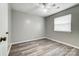 A bright bedroom featuring light gray walls, a ceiling fan, and wood-look laminate flooring at 1212 Robinhood Cir, Charlotte, NC 28227