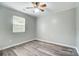 A bright bedroom featuring light gray walls, a ceiling fan, and wood-look laminate flooring at 1212 Robinhood Cir, Charlotte, NC 28227