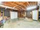 Spacious unfinished garage with wood frame, shelving, and overhead door at 1212 Robinhood Cir, Charlotte, NC 28227