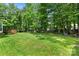 Spacious backyard features a lush lawn, mature trees, and a wooden deck, perfect for outdoor enjoyment at 15001 Arrowgrass Way, Charlotte, NC 28278