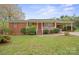 Charming brick home featuring a covered porch, well-kept lawn, and a convenient carport at 303 Windy Rush Rd, Kannapolis, NC 28081