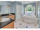 Elegant bathroom featuring a soaking tub, a glass-enclosed shower, and dual vanities with dark countertops at 338 Fairfield Ct, Mount Gilead, NC 27306