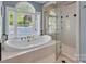 Elegant bathroom with a soaking tub, a glass-enclosed shower, and a large, sunlit window at 338 Fairfield Ct, Mount Gilead, NC 27306