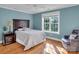 Relaxing bedroom featuring hardwood floors, soft blue walls, and a bright window overlooking the yard at 338 Fairfield Ct, Mount Gilead, NC 27306