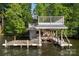 Multi-level boat dock and sun deck on a serene lake, surrounded by lush greenery and a glimpse of a house in the distance at 338 Fairfield Ct, Mount Gilead, NC 27306