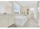 Bright bathroom featuring a white tub, double vanity, and glass shower with neutral tile and fixtures at 345 Somerled Way, Waxhaw, NC 28173