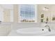 Brightly lit bathroom featuring a modern, tiled tub, vanity with countertop, and large window at 345 Somerled Way, Waxhaw, NC 28173