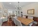 Elegant dining room with a long wooden table, chandelier, and natural light at 5854 Crimson Oak Ct, Harrisburg, NC 28075
