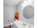 Bright powder room featuring a round mirror, grey walls, and wood-look flooring at 6730 Gold Wagon Ln, Mint Hill, NC 28227