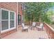Relax on this brick home's back deck featuring comfortable seating and tranquil wooded views at 6730 Gold Wagon Ln, Mint Hill, NC 28227