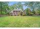 Traditional two-story brick home with a lush green lawn and mature trees providing ample shade at 6730 Gold Wagon Ln, Mint Hill, NC 28227
