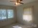 Bright bedroom with neutral walls, two windows with decorative drapes, and a ceiling fan at 701 Dakota St, Kannapolis, NC 28083
