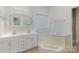 Bright bathroom with a soaking tub, dual sinks, decorative mirror and tiled floors at 7900 Gilead Rd, Huntersville, NC 28078