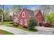 Side exterior view of a red brick home featuring elegant arched windows, landscaping, and an attached garage at 101 Saddletree Rd, Lincolnton, NC 28092