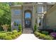 A close up of the home's grand entrance, framed by a stone archway, bay windows, and manicured greenery at 1029 Seminole Dr, Waxhaw, NC 28173