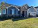 Charming home with a stone facade, blue siding, a well-manicured lawn, and a two-car garage at 1468 Honey Trl, Monroe, NC 28112