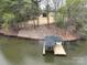 Aerial view of a lakeside property featuring a house, and a private boat dock, all surrounded by lush greenery at 15170 Cove Point Ln, Norwood, NC 28128