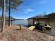 Lakefront boathouse featuring a covered slip, boat lift, and dock for easy lake access and enjoyment at 15170 Cove Point Ln, Norwood, NC 28128
