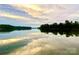 A serene and tranquil lake view reflecting the sky, framed by lush greenery at 15170 Cove Point Ln, Norwood, NC 28128