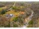 Aerial view showing buildings, creek, and wooded landscape, highlighting the serene and secluded setting at 1595 Cheatham Ford Rd, Hiddenite, NC 28636