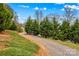 Gravel driveway lined with mature trees and lush green ground cover at 1595 Cheatham Ford Rd, Hiddenite, NC 28636