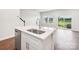 Modern kitchen island featuring a stainless steel sink, white cabinets, and hardwood floors in the living area at 1910 Old Rivers Rd, Concord, NC 28027
