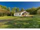 Quaint yellow cottage with a well-maintained lawn, charming porch, and surrounded by lush greenery at 212 W Doc Garris Rd, Lancaster, SC 29720
