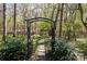 Backyard featuring a decorative iron gate leading to a serene wooded area with stepping stones at 2815 Providence Spring Ln, Charlotte, NC 28270