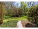 Landscaped backyard featuring a stone pathway leading to a wooded area, enhancing privacy and natural beauty at 2815 Providence Spring Ln, Charlotte, NC 28270