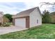 Exterior view of a detached garage with brick accents, white garage door, and green lawn at 301 Prairie Rose Ct, Waxhaw, NC 28173