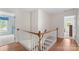 Upstairs hallway with hardwood floors, white banister, wood railing, and neutral paint, connecting multiple bedrooms at 301 Prairie Rose Ct, Waxhaw, NC 28173