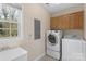 Functional laundry room equipped with modern washer and dryer, sink, cabinet storage, and window at 301 Prairie Rose Ct, Waxhaw, NC 28173