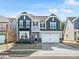 Two-story home features a two-car garage, gray siding, black shutters, and well-maintained landscaping at 3036 Whipcord Dr, Waxhaw, NC 28173