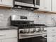 Close-up of a stainless steel stove and microwave with white cabinets and subway tile backsplash at 3036 Whipcord Dr, Waxhaw, NC 28173